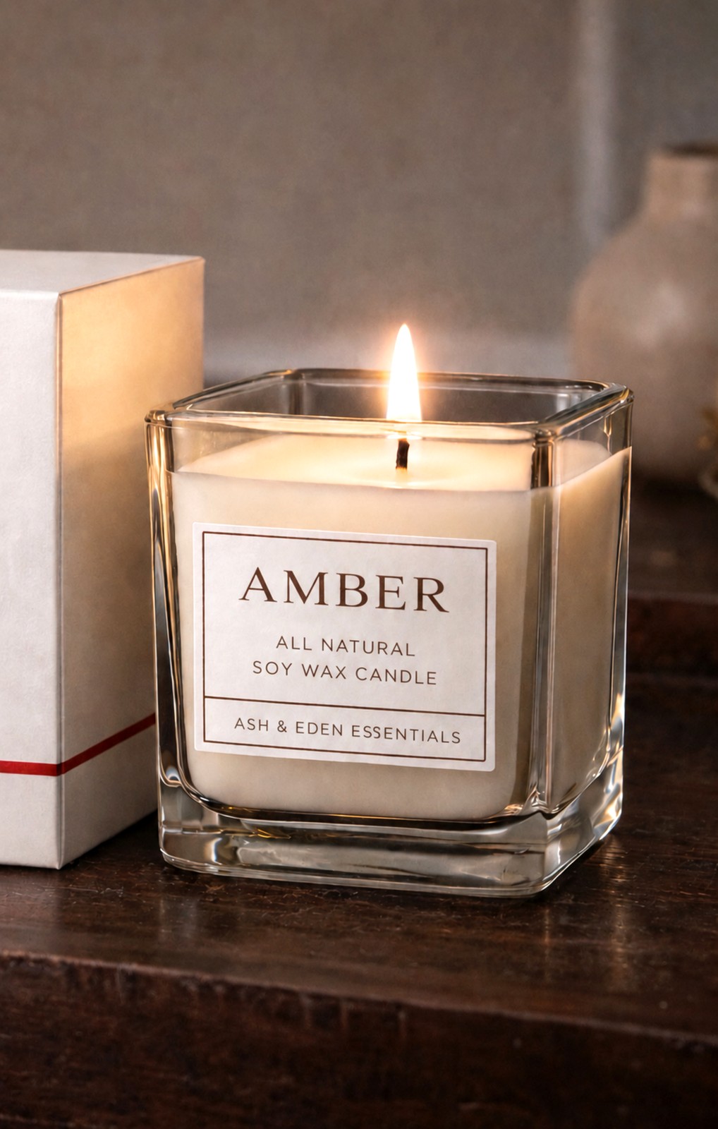 Ash & Eden Essentials Amber soy candle lit on a wood table